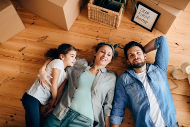High angle view of happy family lying down on the floor after moving into a new home. 