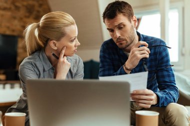 Young couple talking while analyzing their budget at home. 
