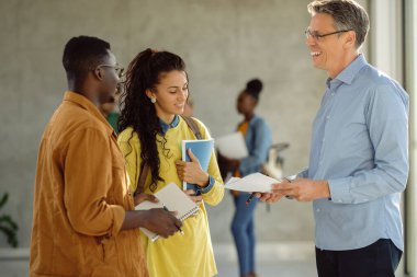 Happy professors and his students communicating at university hallway. 