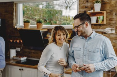 Happy couple having fun while drinking wine in the kitchen. 