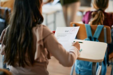 Close-up of elementary student getting A+ grade on a test at school.