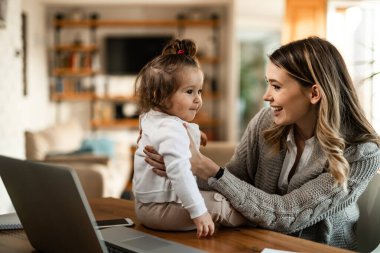 Young happy mother spending time with her small daughter at home.