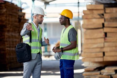 African American worker getting instructions from his manager while working at wood warehouse.