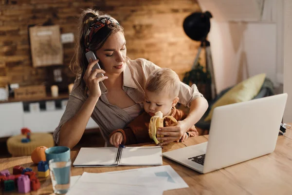 Single Mother Feeding Her Son Banana While Communicating Mobile Phone — Φωτογραφία Αρχείου