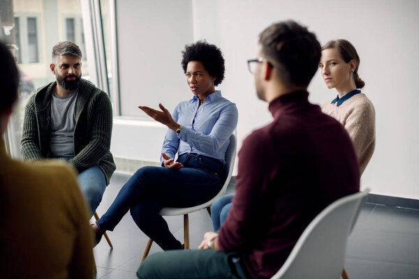 African American businesswoman talking while being on group therapy at medical center. 