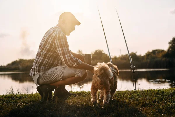 Senior Man Enjoying His Dog While Fishing River Sunset — Stok fotoğraf