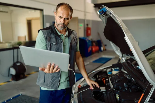 Auto Repairman Using Laptop While Examining Car Engine Workshop — Stock fotografie
