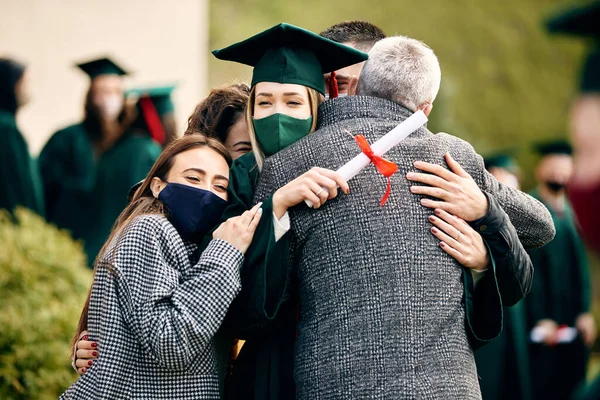 Happy student hugs with her supportive family on graduation day during COVID-19 pandemic.