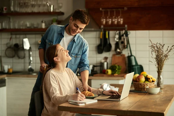 Happy Man Serving Croissant His Wife Who Working Computer Home — Stockfoto