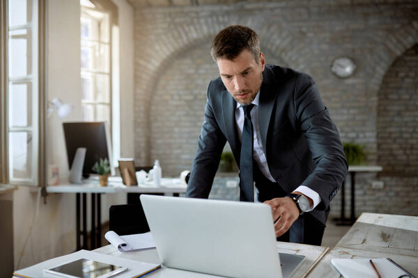 Male entrepreneur using computer while reading an e-mail in the office. 