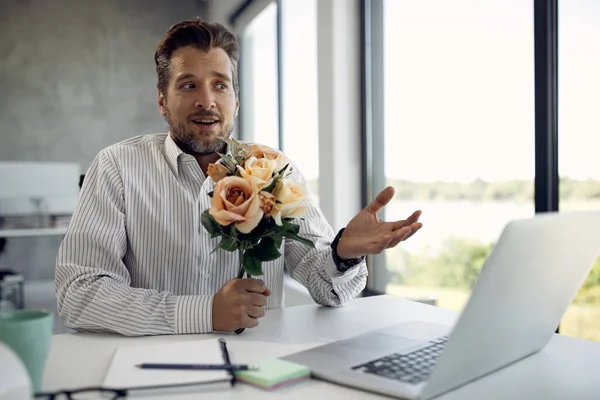 Uncertain Businessman Holding Bouquet Flowers Talking Online Date Laptop Office — Φωτογραφία Αρχείου