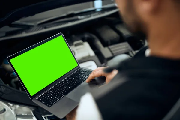 Close-up of mechanic running engine diagnostic on laptop at auto repair shop. Copy space.