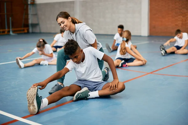 Black School Boy Stretching Floor Help Teacher While Warming Exercise — Foto de Stock
