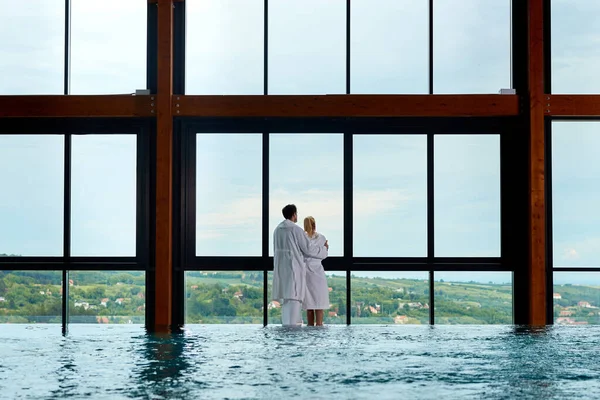 Rear View Embraced Couple Bathrobes Spending Day Spa Looking Window — Fotografia de Stock