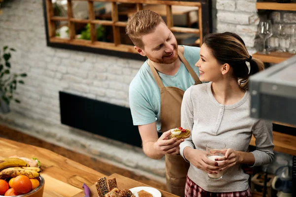 Happy Man Talking His Girlfriend While Offering Her Sandwich Breakfast — Stockfoto