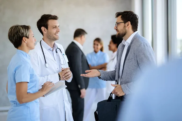 Happy Healthcare Workers Communicating Businessman While Standing Lobby Hospital — Stockfoto