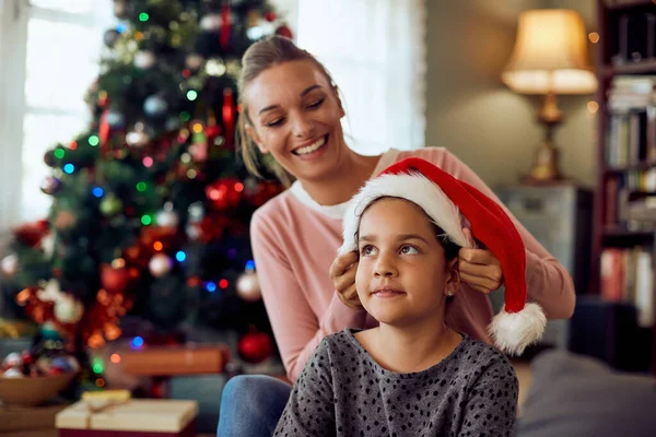 Happy Mother Putting Santa Hat Daughter Head Christmas Day Home — ストック写真