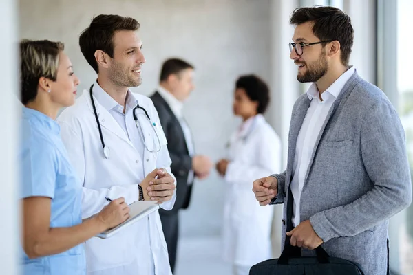 Happy Doctor Nurse Communicating Businessman While Standing Hallway Medical Clinic — Foto de Stock