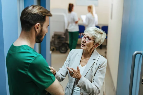Worried Mature Woman Talking Male Surgeon While Standing Lobby Medical — Foto de Stock