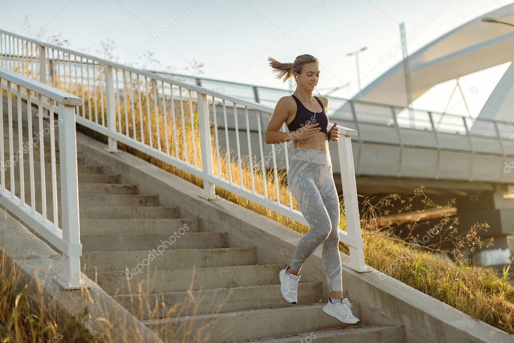 Full length of athletic woman running down the staircase while exercising outdoors. 