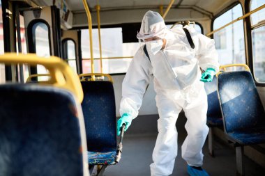 Disinfectant worker spraying inside of a public bus in order to prevent spread of coronavirus. 