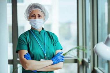 Portrait of surgeon standing with her arms crossed at medical clinic and looking at camera.