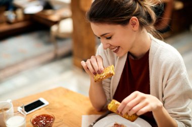 Happy woman having pastry for breakfast at dining table. 
