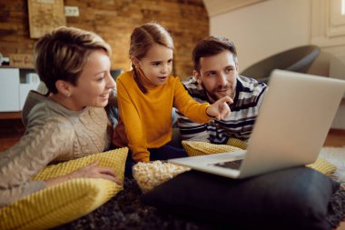 Happy family using laptop ad surfing the net while relaxing at home. 