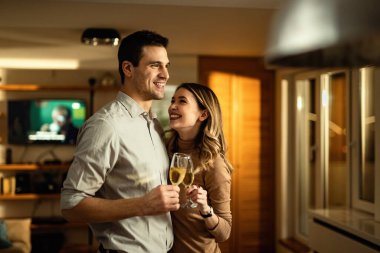 Young couple in love having fun while toasting with Champagne in the living room. 