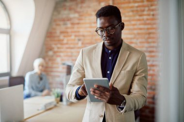 Young black businessman using touchpad while working in the office.