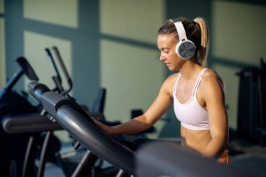 Athletic woman adjusting speed on running track while exercising in a gym. 