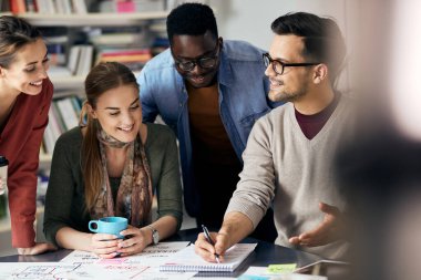 Young entrepreneur taking notes while brainstorming with his colleagues during creative meeting in the office. 