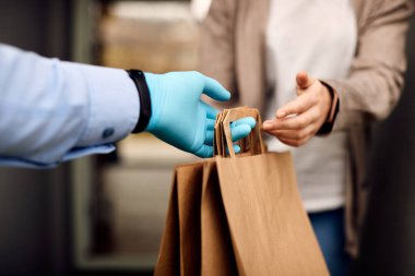 Close-up of courier delivering food to female customer during coronavirus pandemic. 