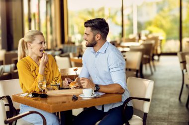 Happy couple talking to each other while eating and having lunch in a restaurant. 