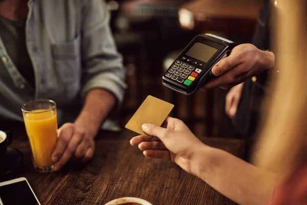 Close-up of customer paying bill with credit card in a pub.