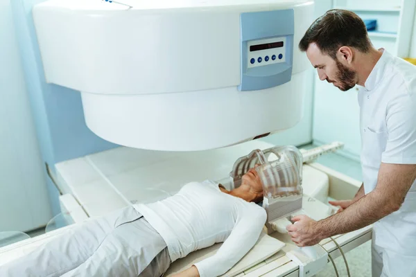 Medical technician preparing his patient who is undergoing for brain MRI san examination in the hospital.