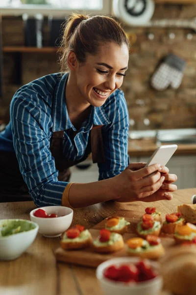 Happy Woman Using Smart Phone Photographing Food She Has Prepared —  Fotos de Stock