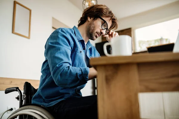 Low angle view of young businessman in wheelchair working at home.