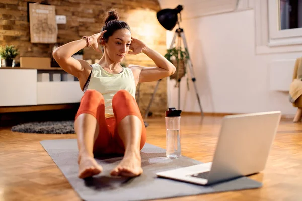 Dedicated Sportswoman Practicing Sit Ups While Using Laptop Having Exercises —  Fotos de Stock