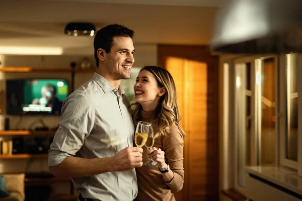 Young couple in love having fun while toasting with Champagne in the living room.