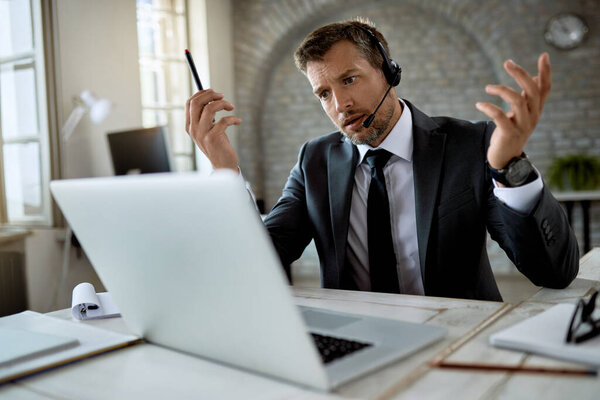 Mid adult businessman using laptop while having online meeting in the office. 