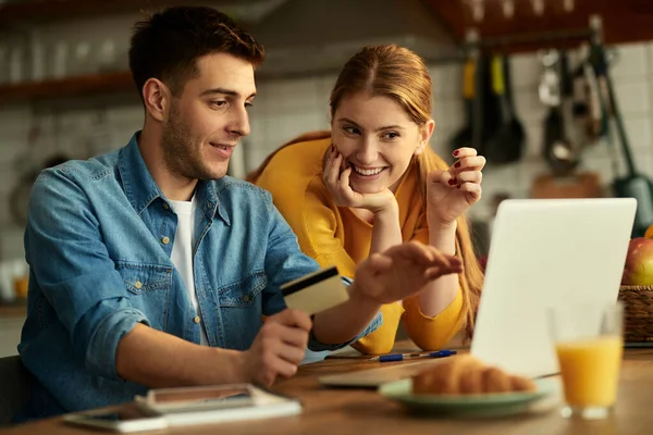 Happy couple using computer and shopping online with credit card at home.