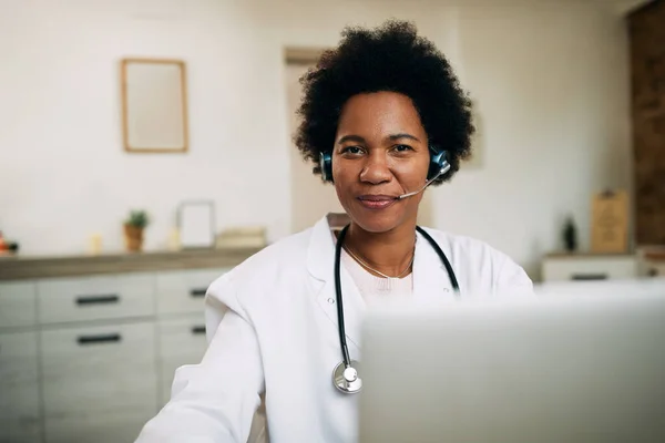 Happy black female doctor working on a computer and looking at camera.