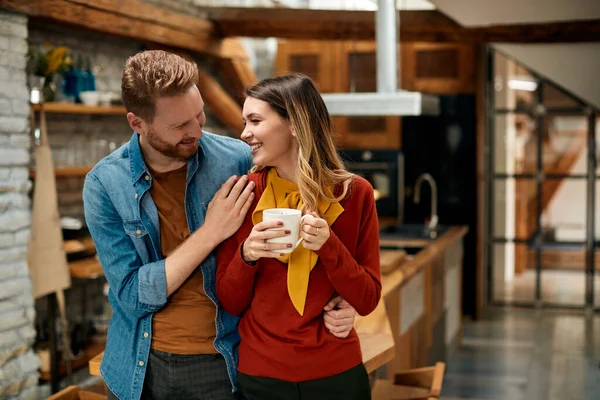 Happy woman having cup of coffee and enjoying in conversation with her boyfriend at home.