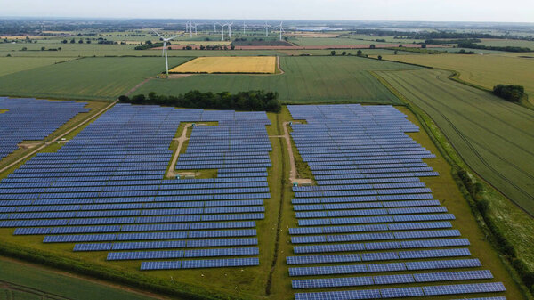 High Angle Aerial view of Drone's Footage of Renewable Solar Panel Power and Windmill Wind Turbine Farms at Countryside of England UK,