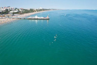 Yüksek Açı Görüntü ve Yüksek Hız Tekneleri ile Okyanus, İngiltere 'nin Bournemouth Sahil Cephesi' nde insanlar eğleniyor ve en sıcak havanın tadını çıkarıyorlar..