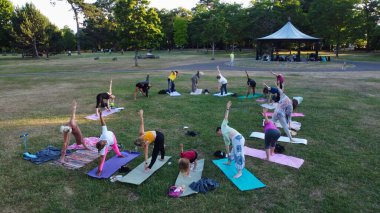 Group of Women Exercising Yoga Together in the Public Park at Sunset of Hot Summer, Aerial High Angle View of Wardown Park Luton England UK