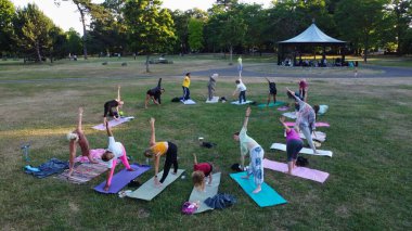 Group of Women Exercising Yoga Together in the Public Park at Sunset of Hot Summer, Aerial High Angle View of Wardown Park Luton England UK