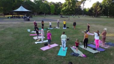 Group of Women Exercising Yoga Together in the Public Park at Sunset of Hot Summer, Aerial High Angle View of Wardown Park Luton England UK