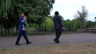 Luton İngiltere 'nin yerel halk parkında 2 Asyalı genç erkek bir bebekle yürüyor.